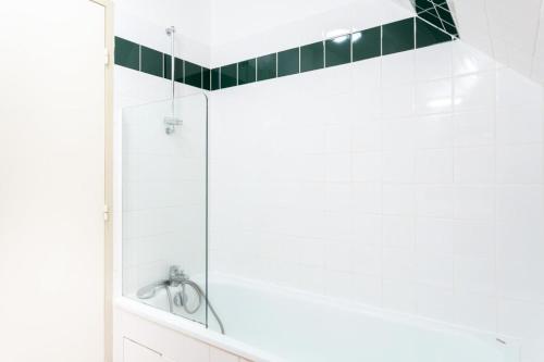 La salle de bains est pourvue d'une douche et de carrelage vert sur le mur. dans l'établissement Résidence Les Belles Rives - maeva Home - Appartement 2 pièces 7 personnes 244, à Argentat