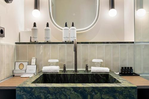 a bathroom with a sink and a mirror at The College Hotel Amsterdam, Autograph Collection in Amsterdam