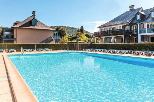 une grande piscine avec des chaises et une maison dans l'établissement Résidence Les Belles Rives - maeva Home - Appartement 2 pièces 5 personnes - Confort MAE-4334, à Argentat