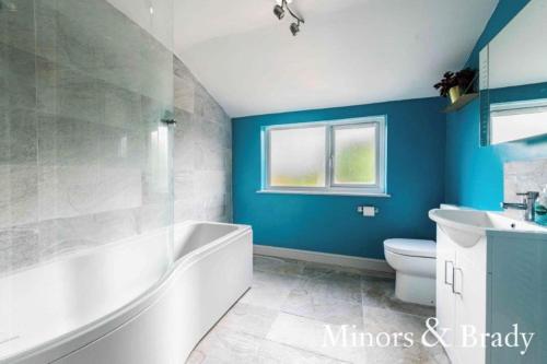 a bathroom with a tub and a toilet and a sink at Modern terrace with large garden & standalone bar in Norwich