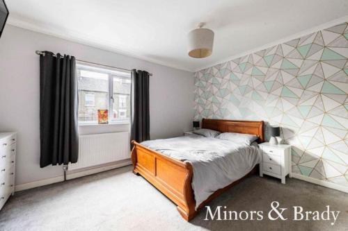 - une chambre avec un lit et un mur géométrique dans l'établissement Modern terrace with large garden & standalone bar, à Norwich