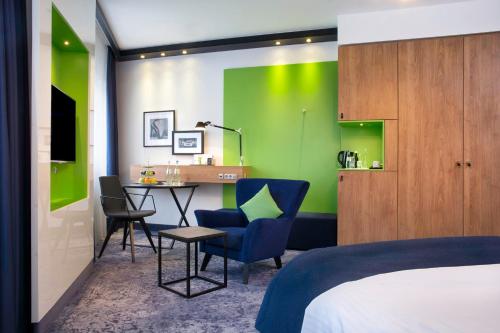 ein Schlafzimmer mit einem Bett, einem Schreibtisch und einer grünen Wand in der Unterkunft Holiday Inn Stuttgart, an IHG Hotel in Stuttgart