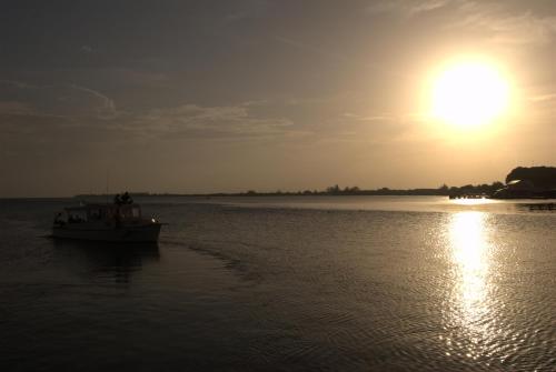 a boat in the water with the sun in the background at Coral View Beach Resort in Utila