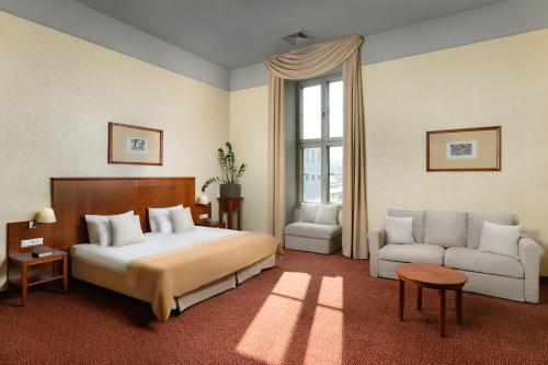 a bedroom with a bed and a couch and a window at Mercure Szekesfehervar Magyar Kiraly in Székesfehérvár