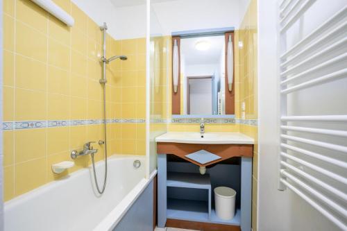 La salle de bains est pourvue de murs jaunes, d'un lavabo et d'une baignoire. dans l'établissement Résidence Port Bourgenay - maeva Home - Appartement 2 pièces 7 personnes - Confort MAE-7054, à Talmont-Saint-Hilaire