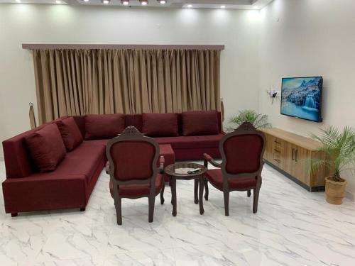a living room with a red couch and two chairs at Holiday Home Family & Groups in Gujrāt