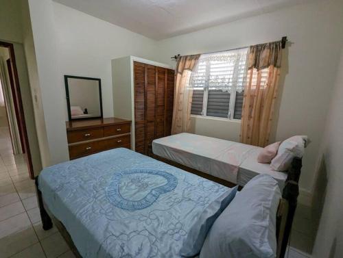 a bedroom with two beds and a dresser and a window at Montserrat Mountain View Retreat in Cudjoe Head