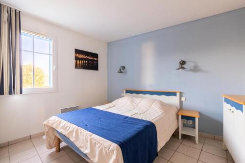 une chambre avec un lit avec une couverture bleue et une fenêtre dans l'établissement Résidence Port Bourgenay - maeva Home - Appartement 3 Pièces 7 Personnes - Sélection MAE-0714, à Talmont-Saint-Hilaire