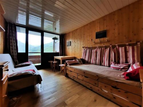 een woonkamer met een bank in een houten muur bij Résidence Alpages - Studio pour 3 Personnes 904 in Les Menuires