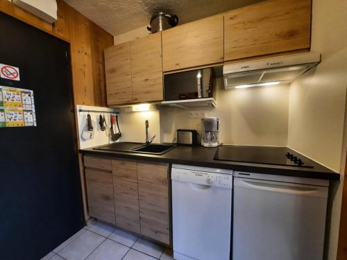 - une petite cuisine avec des placards en bois et un lave-vaisselle dans l'établissement Résidence Aravis - Studio pour 3 personnes avec blacon exposé Sud MAE-5944, aux Menuires