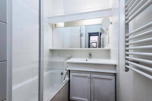 La salle de bains blanche est pourvue d'un lavabo et d'un miroir. dans l'établissement Village Pont Royal en Provence - maeva Home - Appartement 2 Pièces 6 Person 804, à Mallemort