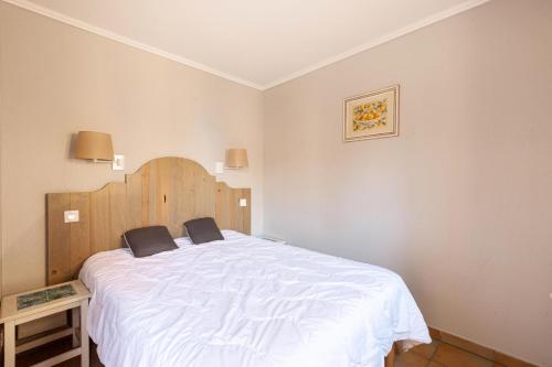 um quarto com uma cama branca e uma cabeceira em madeira em Village Pont Royal en Provence - maeva Home - Appartement 2 Pièces 6 Person 814 em Mallemort
