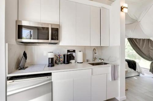 a white kitchen with a sink and a microwave at Unique Escapes - Modern Luxury Geodome in Monticello