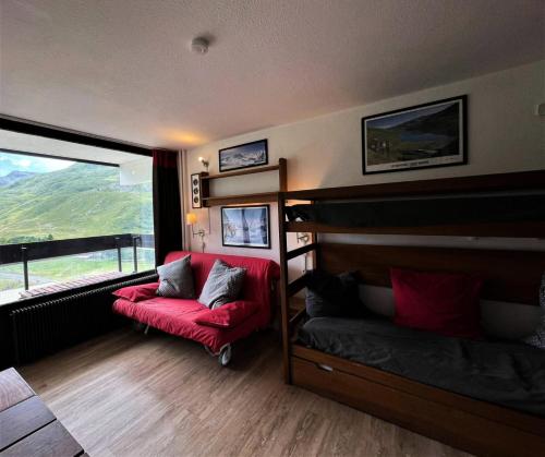 - une chambre avec des lits superposés, un canapé rouge et une fenêtre dans l'établissement Résidence Dorons - Studio pour 3 Personnes 974, aux Menuires