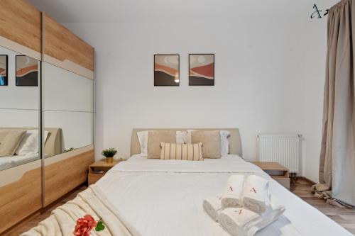 a bedroom with a large white bed with two towels at Maia 1BDR with Parking in Mogoşoaia