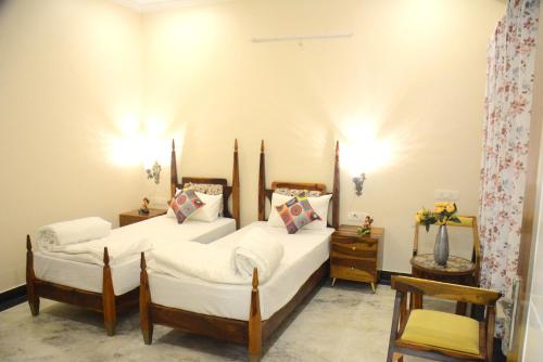 a bedroom with two beds and two chairs at Gupta Vilas - A Boutique Homestay in Agra