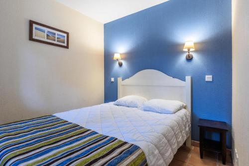 une chambre avec un lit avec un mur bleu dans l'établissement Le Domaine du Golf de Pinsolle - maeva Home - Appartement 2 pièces 5 personnes - Confort MAE-7574, à Soustons