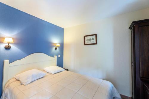 ein Schlafzimmer mit einem weißen Bett mit blauen Wänden in der Unterkunft Le Domaine du Golf de Pinsolle - maeva Home - Appartement 2 pièces 5 person 674 in Soustons