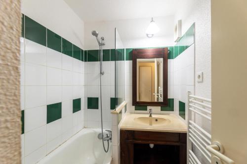 ein Badezimmer mit einem Waschbecken, einer Badewanne und einem Spiegel in der Unterkunft Le Domaine du Golf de Pinsolle - maeva Home - Appartement 2 pièces 5 person 674 in Soustons