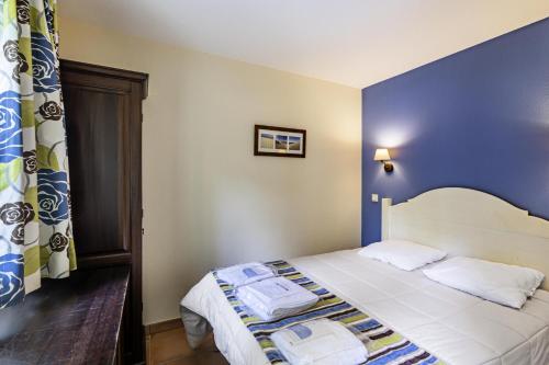 une chambre avec un lit avec un mur bleu dans l'établissement Le Domaine du Golf de Pinsolle - maeva Home - Appartement 2 pièces 6 personnes - Sélection MAE-2694, à Soustons