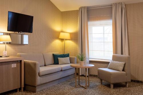 a hotel room with a couch and a chair and a window at City Hotels Algirdas in Vilnius