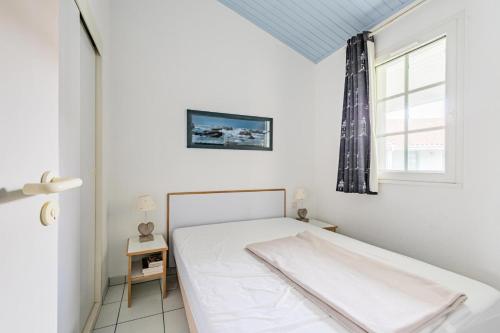 un lit blanc dans une chambre avec une fenêtre dans l'établissement Résidence Port Bourgenay - maeva Home - Appartement 2 pièces 6 personnes - Sélection MAE-6314, à Talmont-Saint-Hilaire