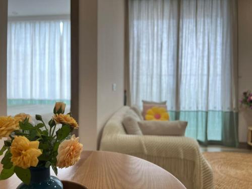 uma sala de estar com um vaso de flores sobre uma mesa em Fami-homestay-ecopark-Căn hộ 1PN 2 giường em Kim Quan
