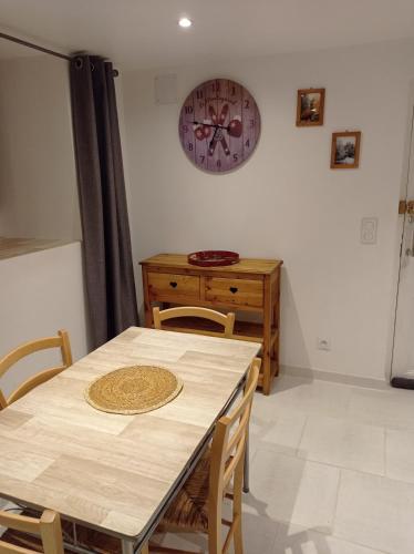 a dining room with a table and a clock on the wall at La marmotte in Briançon