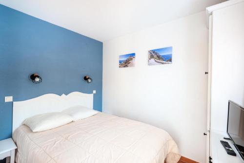 - une chambre avec un lit blanc et un mur bleu dans l'établissement Village Pont Royal en Provence - maeva Home - Appartement 2 pièces 6 personnes - Sélection MAE-2134, à Mallemort