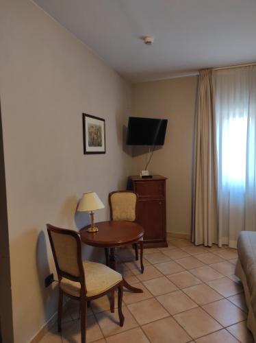 a living room with a table and chairs and a tv at Hotel Le Mura in Foligno