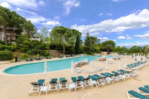 une grande piscine avec chaises et parasols dans l'établissement Les maisons Le Rouret - maeva Home - Maison 3 pièces 6 personnes - Sélection MAE-5094, à Grospierres