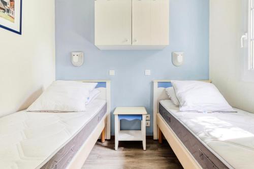 - 2 lits dans une chambre avec une table de chevet dans l'établissement Port du Crouesty Cap'Océan - maeva Home - Appartement 2 pièces 4 personnes - Sélection MAE-4534, à Arzon