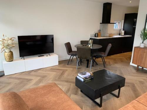 a living room with a flat screen tv and a table at Luxe boshuisje Arlo in Ermelo! in Ermelo