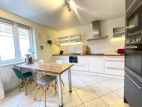 une cuisine avec une table en bois et des chaises bleues dans l'établissement Le gîte d'Emma, à Sainte-Croix-en-Plaine