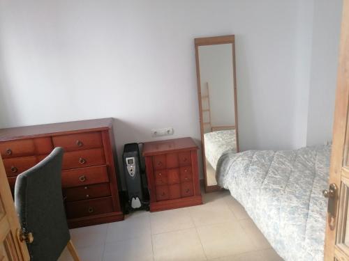 Schlafzimmer mit einem Bett, einer Kommode und einem Spiegel in der Unterkunft casa la salud in Málaga