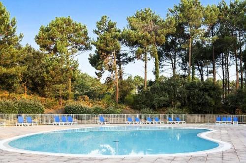 - une piscine avec des chaises et des arbres bleus dans l'établissement Le Domaine du Golf de Pinsolle - maeva Home - Appartement 2 pièces 6 personnes - Confort MAE-9354, à Soustons