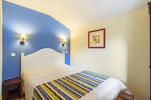 une chambre avec un lit avec un mur bleu dans l'établissement Le Domaine du Golf de Pinsolle - maeva Home - Appartement 2 pièces 6 personnes - Confort MAE-9354, à Soustons