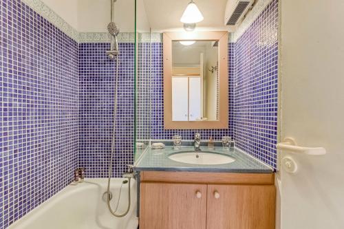 La salle de bains est pourvue de carrelage bleu, d'une baignoire et d'un lavabo. dans l'établissement Résidence le Hameau de Cap Esterel - maeva Home - Appartement 2 pièces 4 personnes - Sélection MAE-0594, à Saint-Raphaël