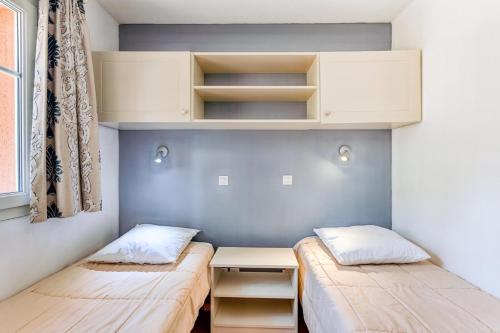 Cette petite chambre comprend deux lits et un bureau. dans l'établissement Résidence Lacanau Les Pins - maeva Home - Appartement 2 pièces 4 personnes - Prestige MAE-0844, à Lacanau