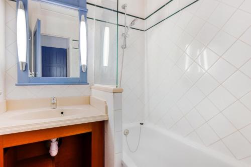 une salle de bain avec un lavabo, un miroir et une baignoire dans l'établissement Résidence Lacanau Les Pins - maeva Home - Appartement 2 pièces 4 personnes - Prestige MAE-0844, à Lacanau