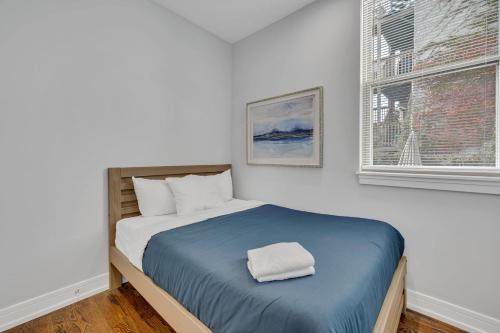 ein Schlafzimmer mit einem Bett mit einer blauen Decke und einem Fenster in der Unterkunft Spacious Bucktown Sanctuary in Chicago