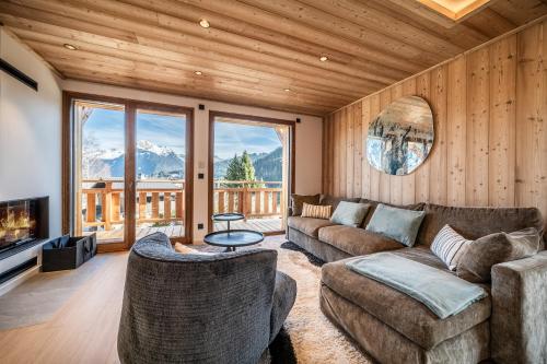 un soggiorno con divano, TV e montagne di Chalet Bellatrix Morzine - by EMERALD STAY a La Côte dʼArbroz