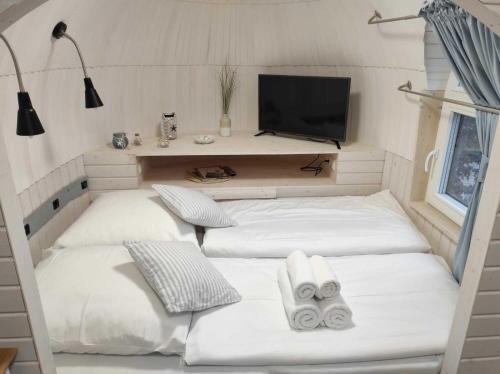 a room with four white beds and a tv at Tiny Igloo Sandström in Belau