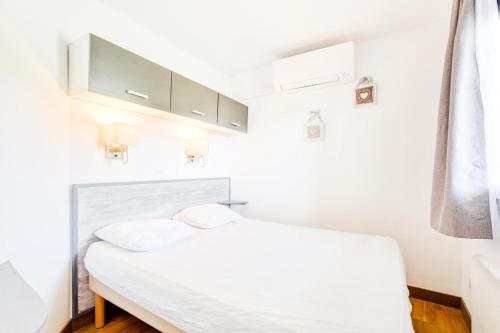 - un lit blanc dans une chambre aux murs blancs dans l'établissement Résidence le Village de Cap Esterel - maeva Home - Appartement 2 pièces 5 personnes - Sélection MAE-5344, à Saint-Raphaël