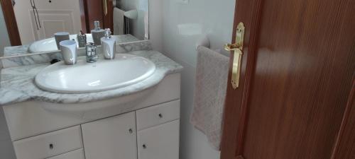bagno con lavandino bianco e specchio di Apartamento Vista Magnifica a Castillo del Reboller