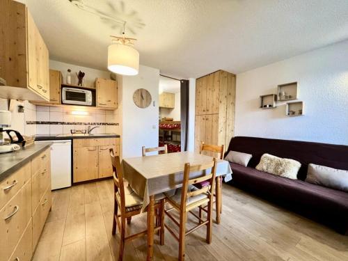 a kitchen and living room with a table and a couch at Résidence Le Zenith - Studio pour 4 Personnes 384 in Notre-Dame-de-Bellecombe