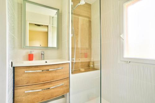 y baño con ducha, lavabo y espejo. en Les maisons du Domaine du Golf de Pinsolle - maeva Home - Maison 3 pièces 6 324, en Soustons