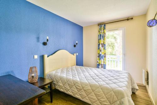 Dormitorio azul con cama y ventana en Les maisons du Domaine du Golf de Pinsolle - maeva Home - Maison 3 pièces 6 324, en Soustons