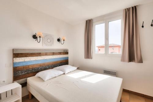 - une chambre avec un lit blanc et 2 fenêtres dans l'établissement Les Appartements aux Restanques du Golfe de St Tropez - maeva Home - Appartement 3 pièces 6 personnes - Sélection - vue Mer MAE-0514, à Grimaud