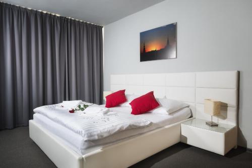 Hotel Atom Třebíč في تيربيك: غرفة نوم بسرير ابيض ومخدات حمراء
